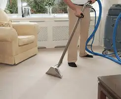 Carpet cleaning professional removing dirt and stains with a hot-water extraction tool in a home, Peoria, IL.