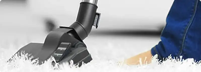 Close-up of a professional vacuuming a white carpet in Dunlap.